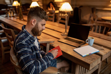Obraz premium Casual business man or freelancer planning his work on notebook, working on laptop computer with smart phone, cup of coffee on table at coffee shop or home office.