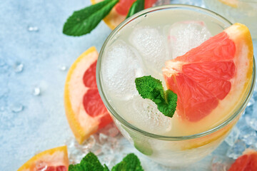 Lemonade drink made from grapefruit, soda water and mint leaves with ice on light blue slate, stone...
