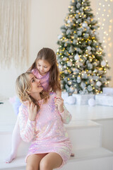 Happy family mother and child daughter near Christmas tree at home