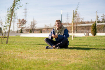 young guy sitting on the lawn grass field and enjoying summer day weather
