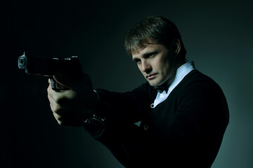 Male portrait in the dark with a gun in his hand - obrazy, fototapety, plakaty