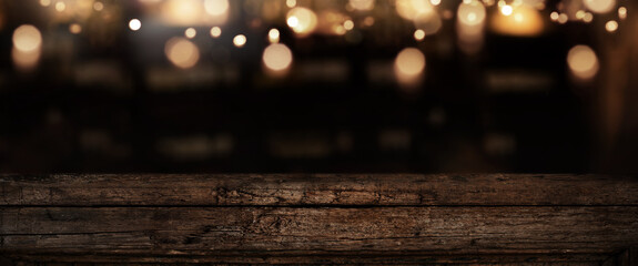 Iluminated old weathered wooden counter in a bar with bokeh lights. Background for decorations and...