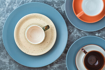 several empty plates and cups of different colors on a concrete background