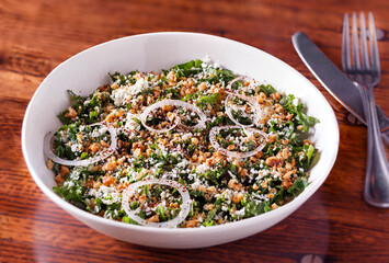 Kale salad with walnuts and feta cheese in a white bowl