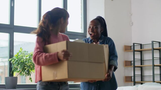 moving, people and real estate concept - women packing boxes at home