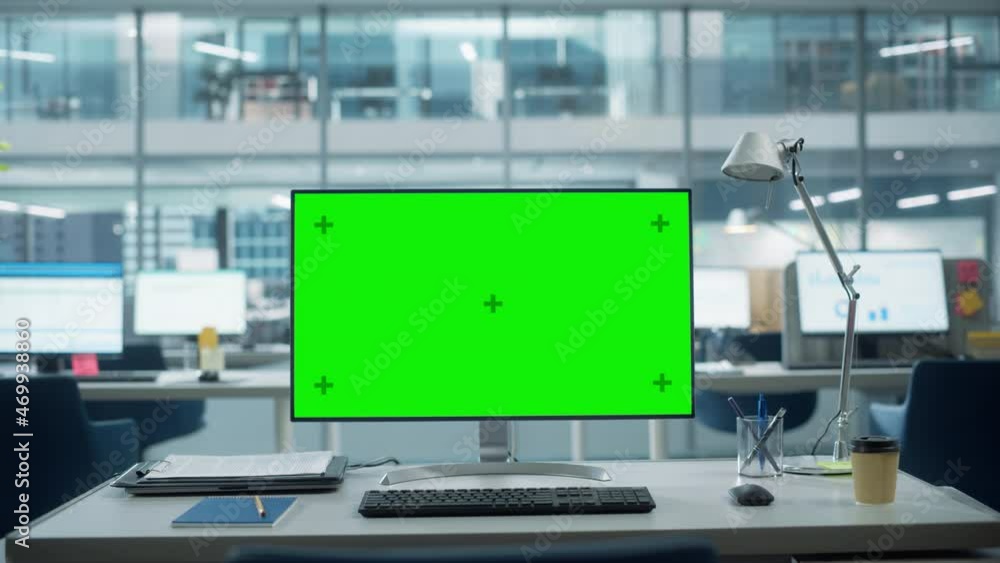 Poster Desktop Computer Monitor with Mock Up Green Screen Chroma Key Display Standing on the Desk in the Modern Business Office. In the Background Glass Wall with Big City Office. Zoom in Shot.