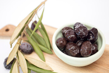 Black olives in a bowl with a branch of an olive tree