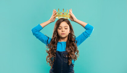 selfish kid with curly hair in princess crown on blue background, egoist