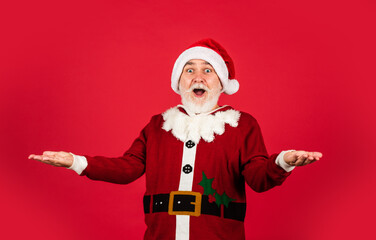 Fototapeta na wymiar You are next. xmas presents and gift shopping time. winter holiday joy. funny senior man in santa claus costume. happy new 2021 year. merry christmas. bearded santa in hat on red background