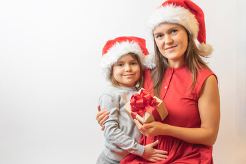 Happy mother and son in Santa hat with Christmas gifts. Cheerful family celebrates Christmas at home. Funny mom and daughter open gift boxes indoors