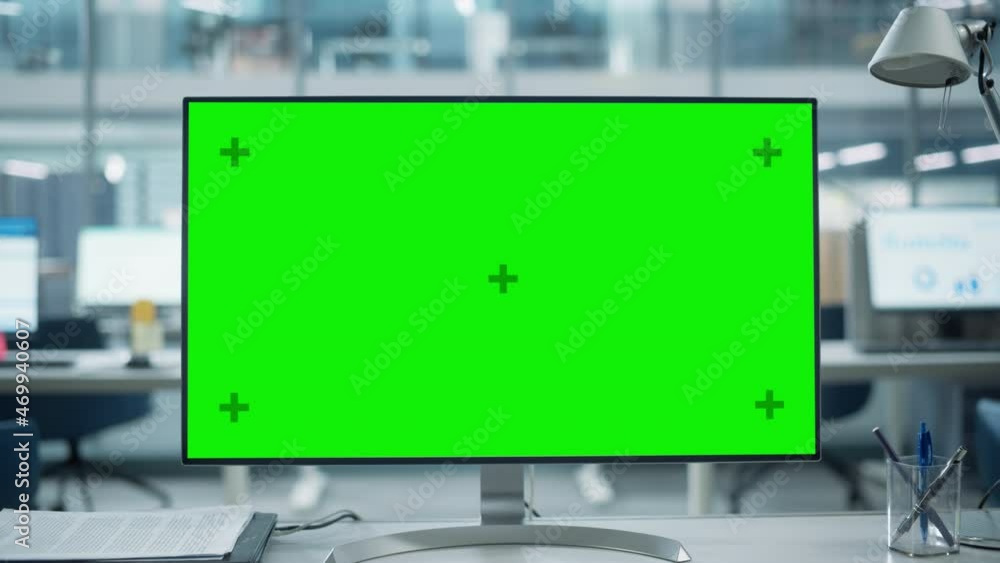 Poster Desktop Computer Monitor with Mock Up Green Screen Chroma Key Display Standing on the Desk in the Modern Business Office. In the Background Glass Wall with Big City Office. Zoom Out Shot.