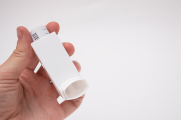 Hand holding asthma inhaler on white background