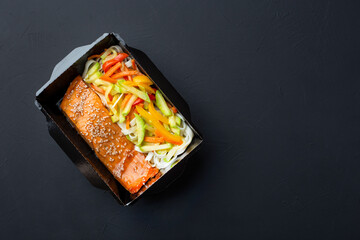 A healthy meal in a lunch box, salmon, pasta, vegetables.