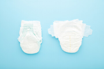 White soft sticky diaper and pants diaper on light blue table background. Pastel color. Closeup....