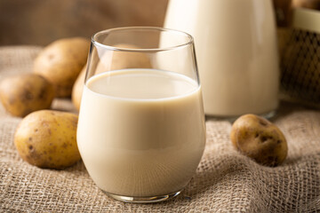 Potato milk alternative non dairy drink in glass on sackcloth, close up. Healthy vegetarian and vegan drink concept with copy space