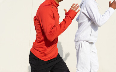 Anonymous african American friends jogging on spot against white wall