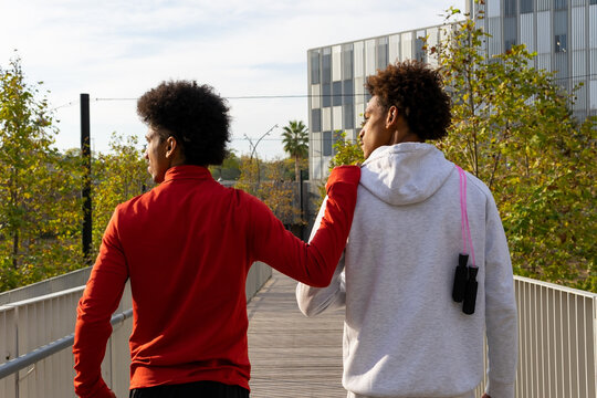 Black sporty men walking on bridge together
