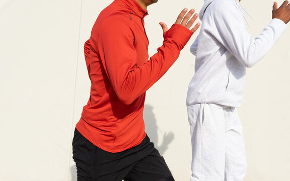 Anonymous african American friends jogging on spot against white wall