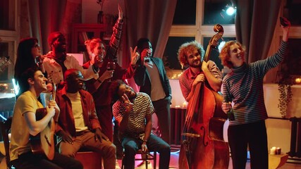 Group of young cheerful people smiling and posing for smartphone camera with music band while taking picture together after concert