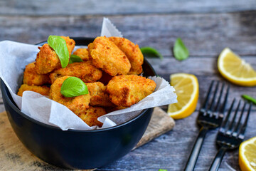 
 Crispy  deep fried home made    chicken strips Breaded  with  almond flour chicken  breast fillets  with chilly peppers and fresh   basil on wooden rustic background. Ketogenic diet food