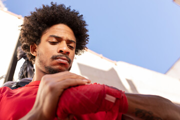 Ethnic man wrapping bandage on hand