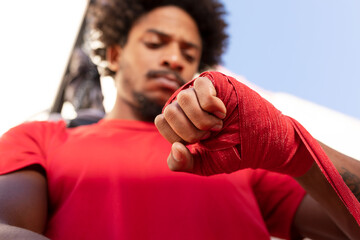 Ethnic man wrapping bandage on hand