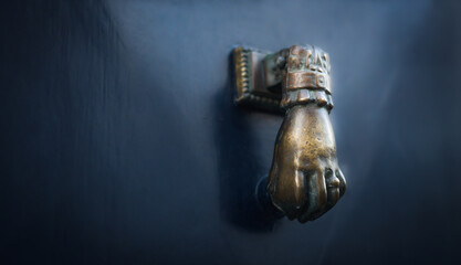 Złota koładka do drzwi przedstawiająca dłoń.
