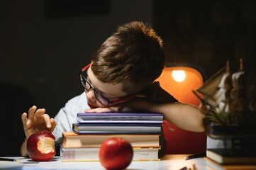 schoolboy doing homework at the table in his room.