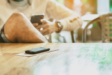 Wireless Calling System Restaurant or Pager Customers System with invoice on table with blur image of man using cellphone in background.Alarm signal when food is done.Queue wireless pager for calling.