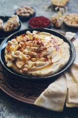 Traditional homemade middle eastern dish - hummus decorated with chickpeas, garlic, olive oil and spices on dark stone table