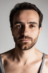 Naklejka premium Close-up portrait of young handsome bearded shirtless man isolated on gray studio background. Natural beauty