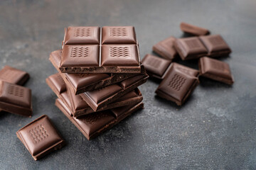Sweet Chocolate tower pieces chocolates. Stack of chocolate pieces. Background with chocolate. recipe Cooking handmade chocolate bar, dessert, candies on black background