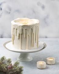 Сake in the shape of a candle. Christmas white cake on a white background with a Christmas decoration, lights or winter holidays pastry food concept.