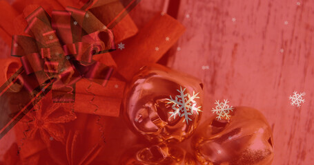 Image of christmas snowflakes falling over cinnamon sticks and decorations