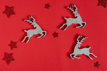 Christmas or New Year composition with reindeer figures and stars on a red background, space for text