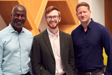 Portrait Of Multi-Cultural Male Business Team Standing In Modern Open Plan Office