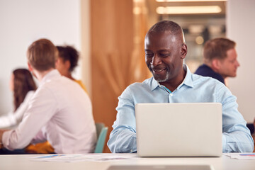 Mature Businessman With Laptop Working On Table In Office Coffee Shop