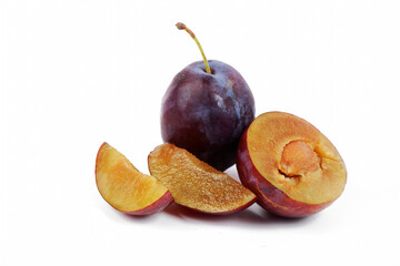 purple plum with plum slices lying next to it, isolated on a white background