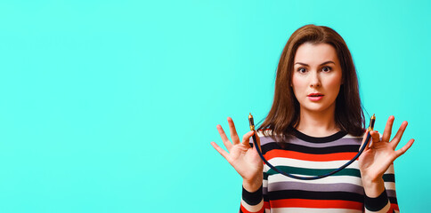 young attractive woman is surprised and holds a digital audio coaxial cable in her hands.