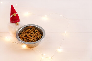 Food for pets in bowl on wooden background and christmas decoration, copy space