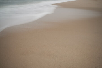Soft focus beach foam rolls onto an empty beach during an Atlantic storm