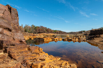 Stunning landscape with rocks dyed orange that are reflected in the Rio Tinto, a river that carries minerals in its waters