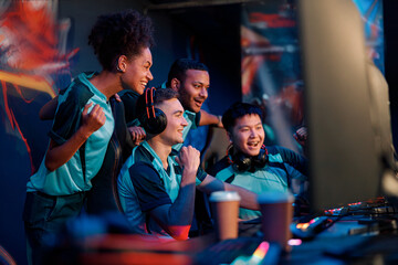 Side view of excited professional cyber gamers team celebrating success while participating in...