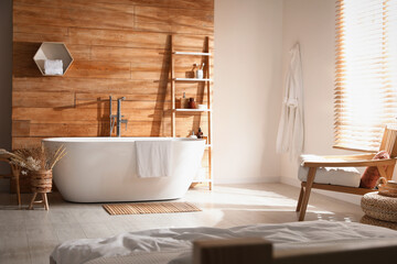 Stylish apartment interior with white bathtub and bed