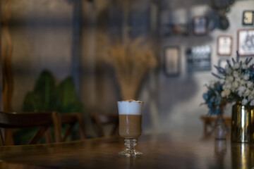 Glass cup with latte is on the table in coffee shop. Glass with caramel cappuccino on the table in...