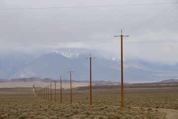 power lines stretching across the empty and desolate California desert with the snow covered Sierra Nevada mountains as a backdrop
