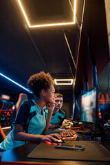 Side view of cute female cybersport gamer playing online game on PC during e-sports tournament in colorful neon lights room © Yaroslav Astakhov