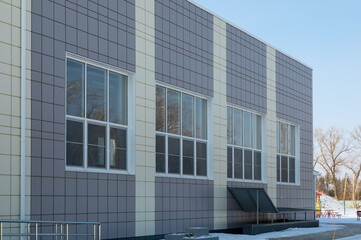grey ventilated facade and large windows on a fragment of an unrecognizable commercial or...