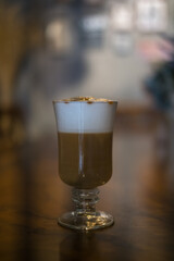 Glass cup with latte is on the table in coffee shop. Glass with caramel cappuccino on the table in the restaurant. Photo for the menu, advertising