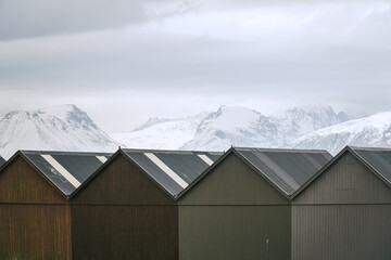 Triangle rooftops of fisherman boat houses and snowy mountains in the north of Norway. Classic scandinavian view.  Alesund.